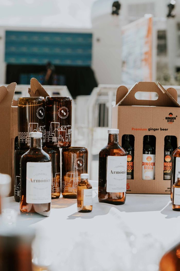 A variety of bottles and ginger beer packs on a table, captured outdoors in bright daylight.