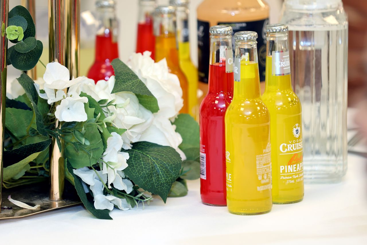 Colorful cocktail bottles with a white floral arrangement on a table setting.